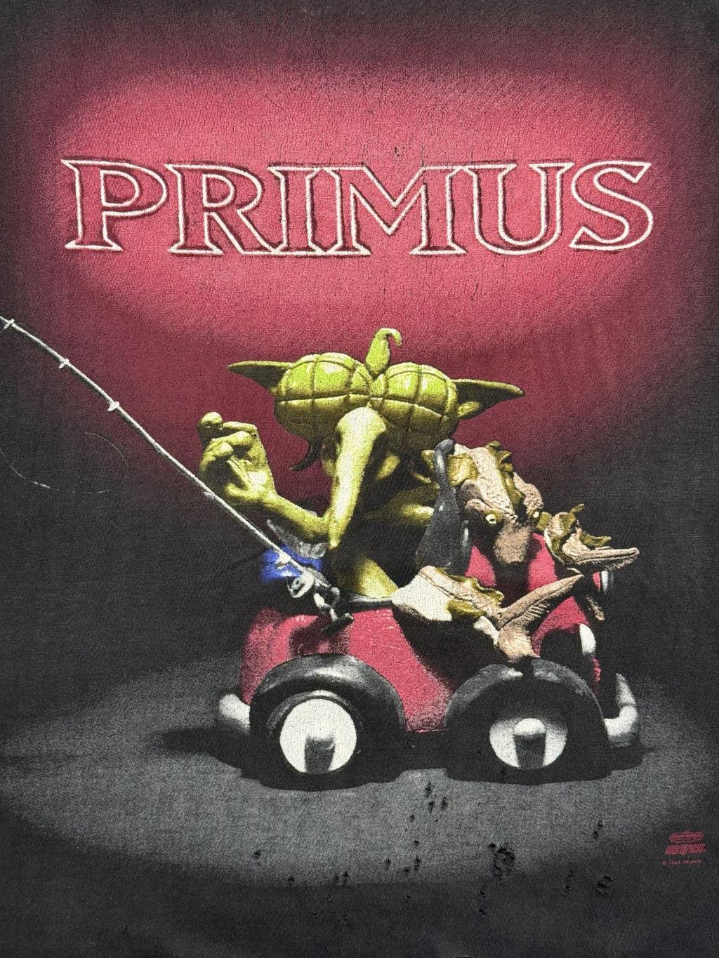 Ausgewaschenes schwarzes Vintage Primus T-Shirt von 1993 zur EP „Miscellaneous Debris“. Stark gealtertes Bandshirt mit Cut-off Ausschnitt und dem ikonischen Knetfiguren-Artwork auf rotem Hintergrund.