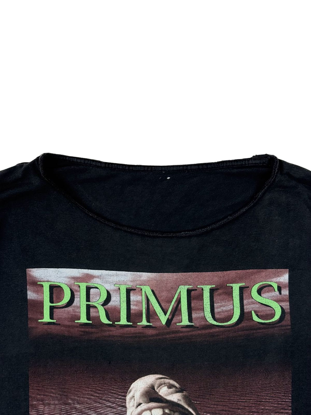 Detailaufnahme des veränderten Halsausschnitts (Cut-out/Distressed-Look) und des neongrünen „PRIMUS“-Schriftzugs auf der Vorderseite.