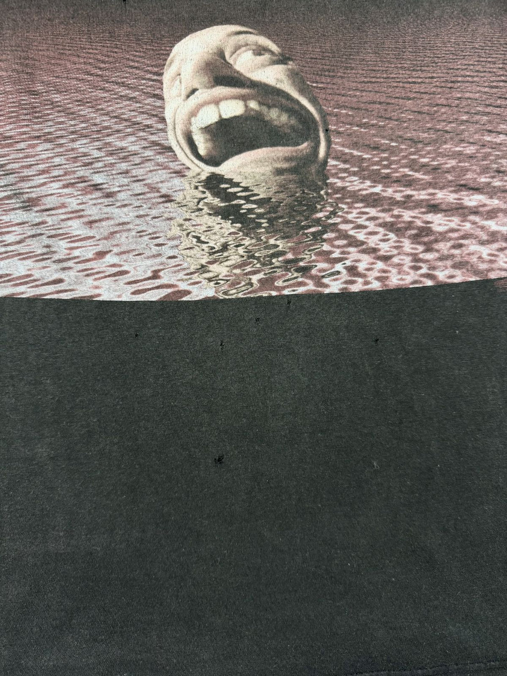 Nahaufnahme des vorderen Siebdrucks mit dem psychedelischen Gesicht im Wasser, passend zum 1995er Album-Artwork. Mehrere Löcher sind unterhalb des Prints zu erkennen.