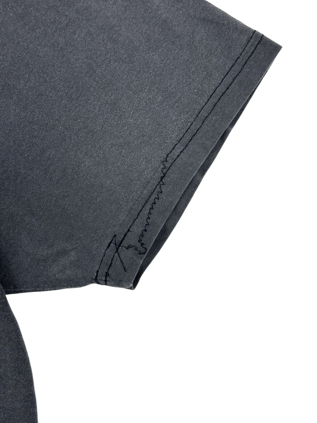 Detailaufnahme eines beschädigten Ärmelbunds mit einer unsauberen, sich lösenden oder nachträglich reparierten schwarzen Naht an einem Vintage-Shirt.