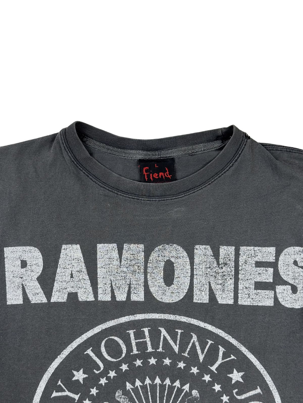 Detailansicht des Kragens und des oberen Prints eines Ramones Vintage-Shirts. Zu sehen ist der weiße, leicht rissige Ramones-Schriftzug im Distressed-Look und das eingenähte schwarze Nackenlabel der Marke Fiend.