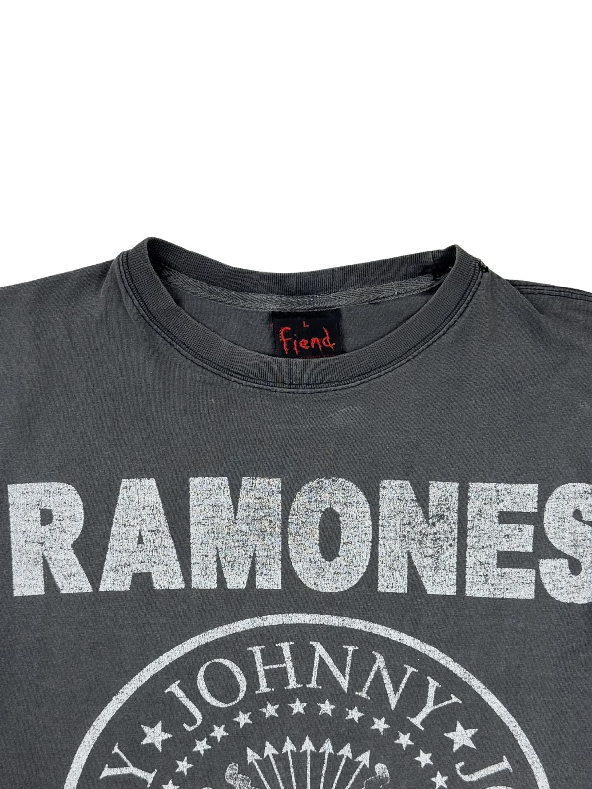 Detailansicht des Kragens und des oberen Prints eines Ramones Vintage-Shirts. Zu sehen ist der weiße, leicht rissige Ramones-Schriftzug im Distressed-Look und das eingenähte schwarze Nackenlabel der Marke Fiend.