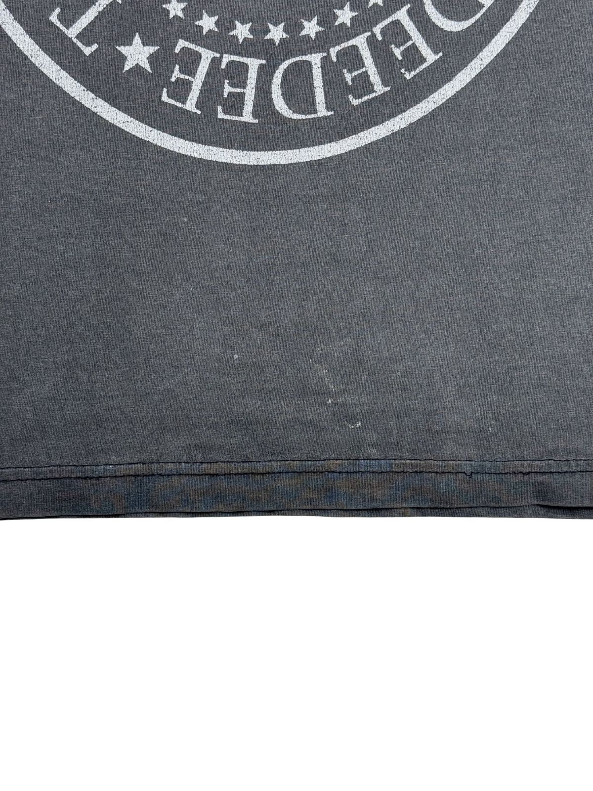 Detailansicht des unteren vorderen Saums des ausgewaschenen, grauen Ramones-Shirts mit doppelter Naht und leichten Verfärbungen bzw. Tragespuren am Stoff.