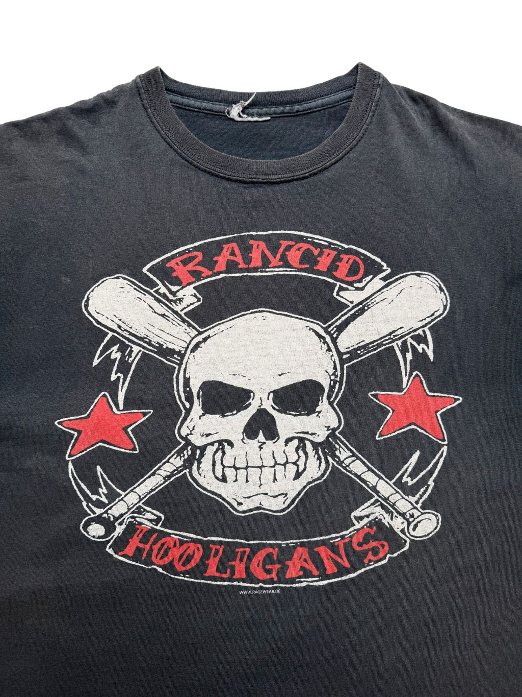Nahaufnahme der oberen Brustpartie mit Blick auf den gerippten Rundhalsausschnitt, das stark abgenutzte Etikett und den vorderen Punkrock-Print.