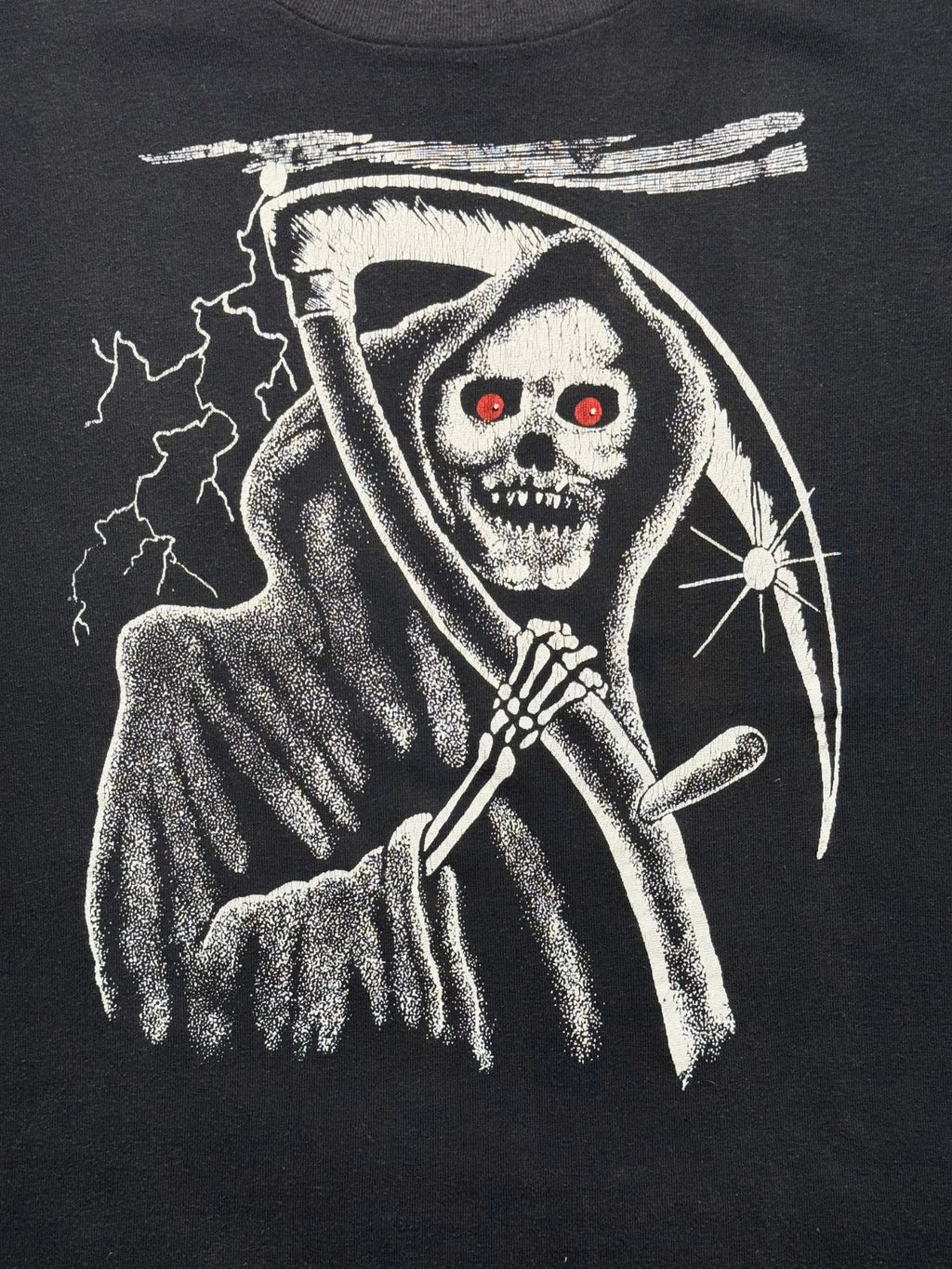 Detailansicht des vorderen Siebdrucks mit dem unheimlichen Sensemann (Grim Reaper), Blitzen und leuchtend roten Augen auf schwarzem Baumwollstoff.
