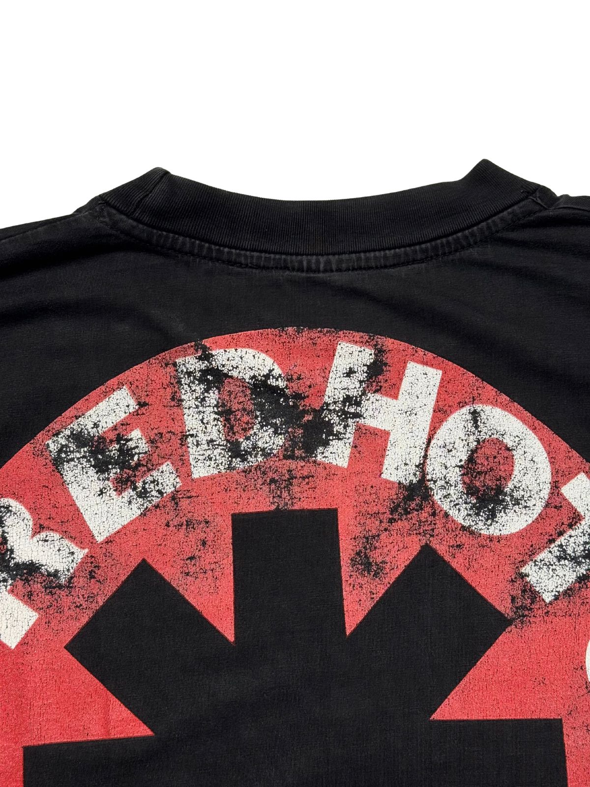 Detailansicht der hinteren Kragennaht mit Blick auf das leicht rissige, rot-weiße Asterisk-Logo der Red Hot Chili Peppers.