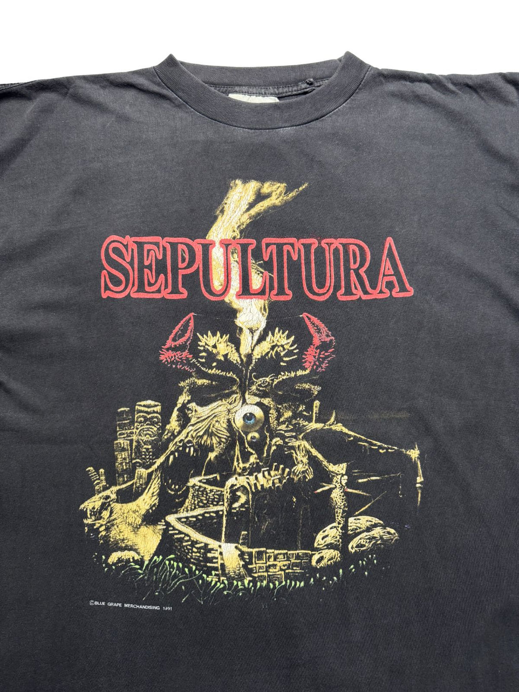 Nahaufnahme der oberen Vorderseite des Trash-Metal-Shirts mit Blick auf den Rundhalsausschnitt, das weiße Stoffetikett und das gealterte Printmotiv.