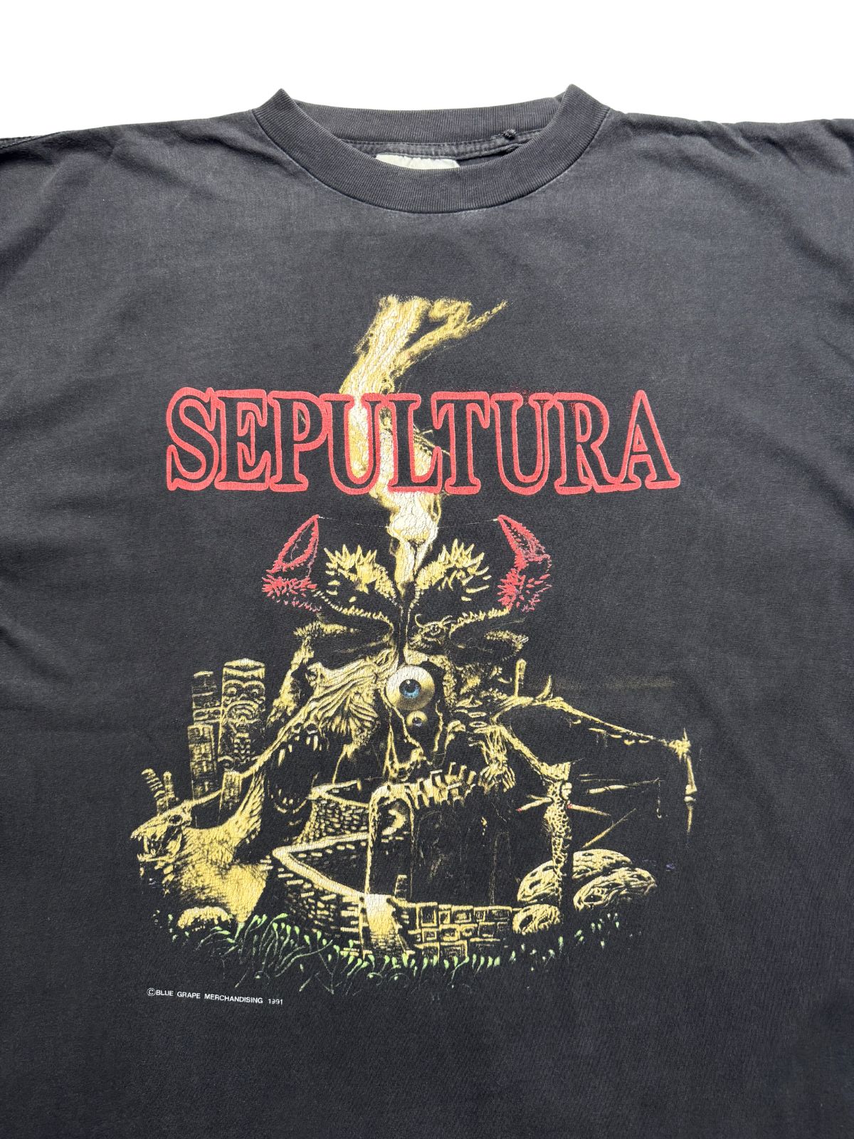 Nahaufnahme der oberen Vorderseite des Trash-Metal-Shirts mit Blick auf den Rundhalsausschnitt, das weiße Stoffetikett und das gealterte Printmotiv.