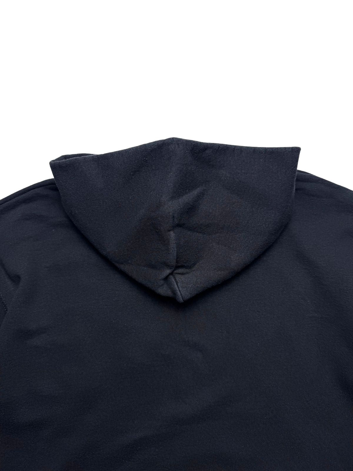 Detailansicht der oberen Rückseite unterhalb des Kapuzenansatzes auf verwaschenem schwarzen Sweatshirt-Stoff.