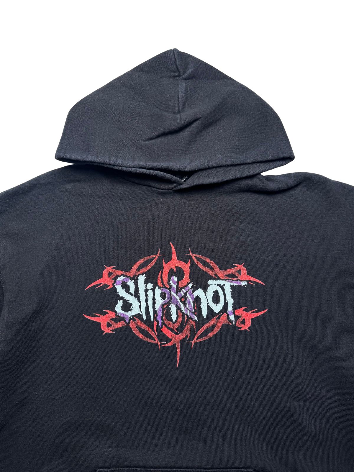 Detailansicht der vorderen Brustpartie unterhalb der Kapuze mit dem rot-lila „Slipknot“-Schriftzug über dem Tribal-Muster und Tribal-S-Logo.