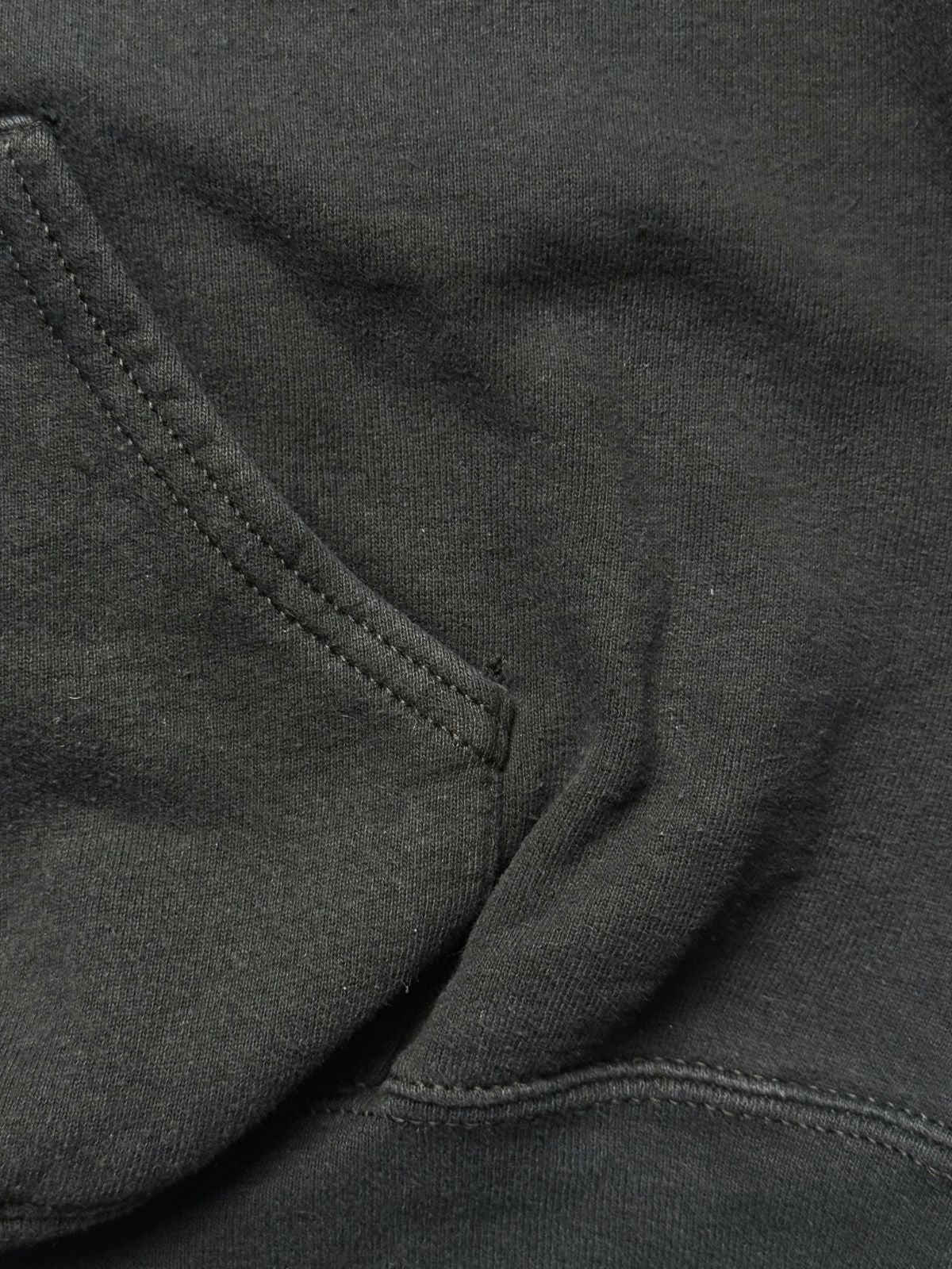Detailansicht der vorderen Kängurutasche und der sauberen Nahtverarbeitung auf dem schweren Baumwoll-Sweatstoff.