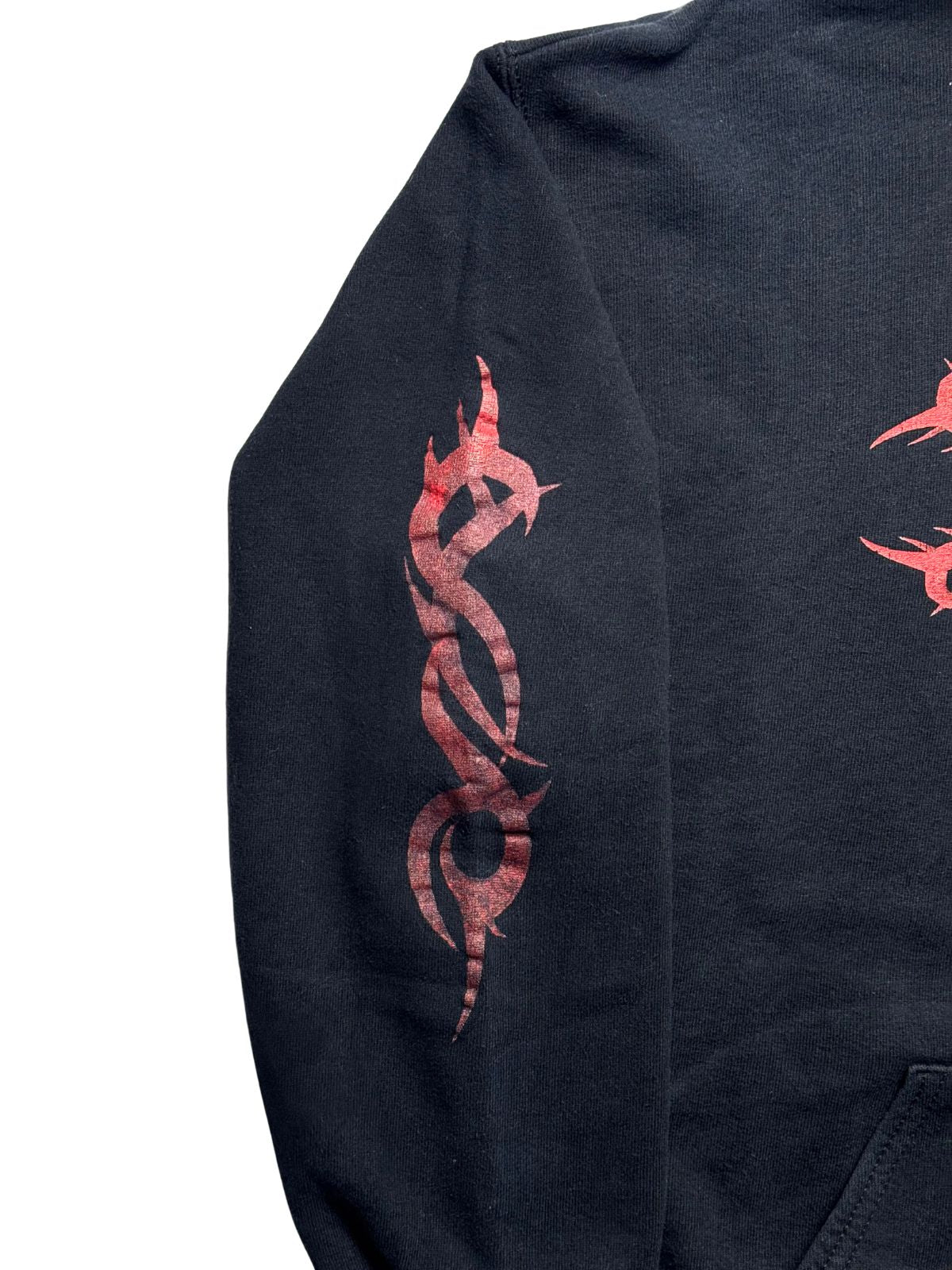 Nahaufnahme des rechten Ärmels mit dem ikonischen, rot gesiebdruckten Tribal-„S“-Logo (Nonagon/Tribal-S) von Slipknot auf verwaschenem schwarzen Sweatstoff.
