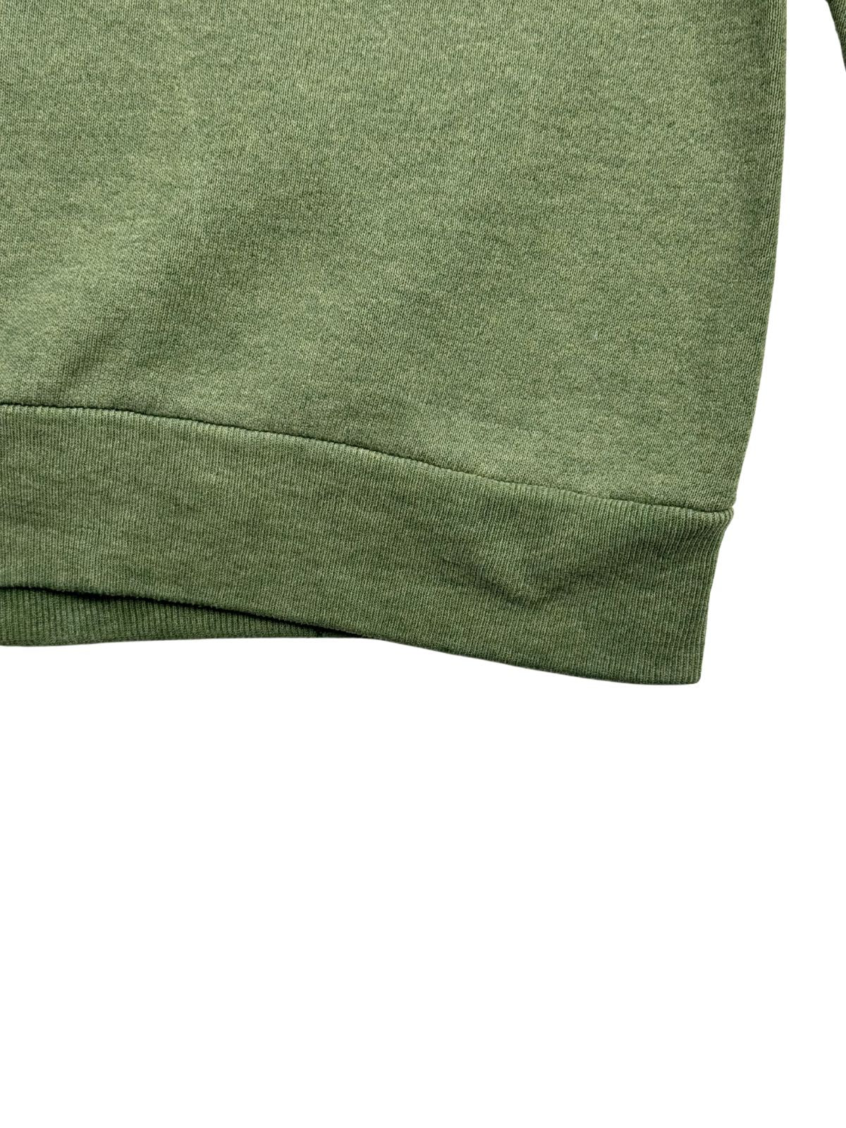 Nahaufnahme des breiten, elastischen Bunds am unteren Saum des grünen Vintage-Pullovers zur Veranschaulichung der Materialstruktur.