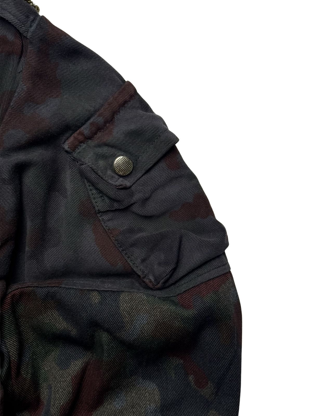 Nahaufnahme der kleinen Oberarmtasche mit strukturiertem Metall-Druckknopf am linken Ärmel der M70-Feldjacke.