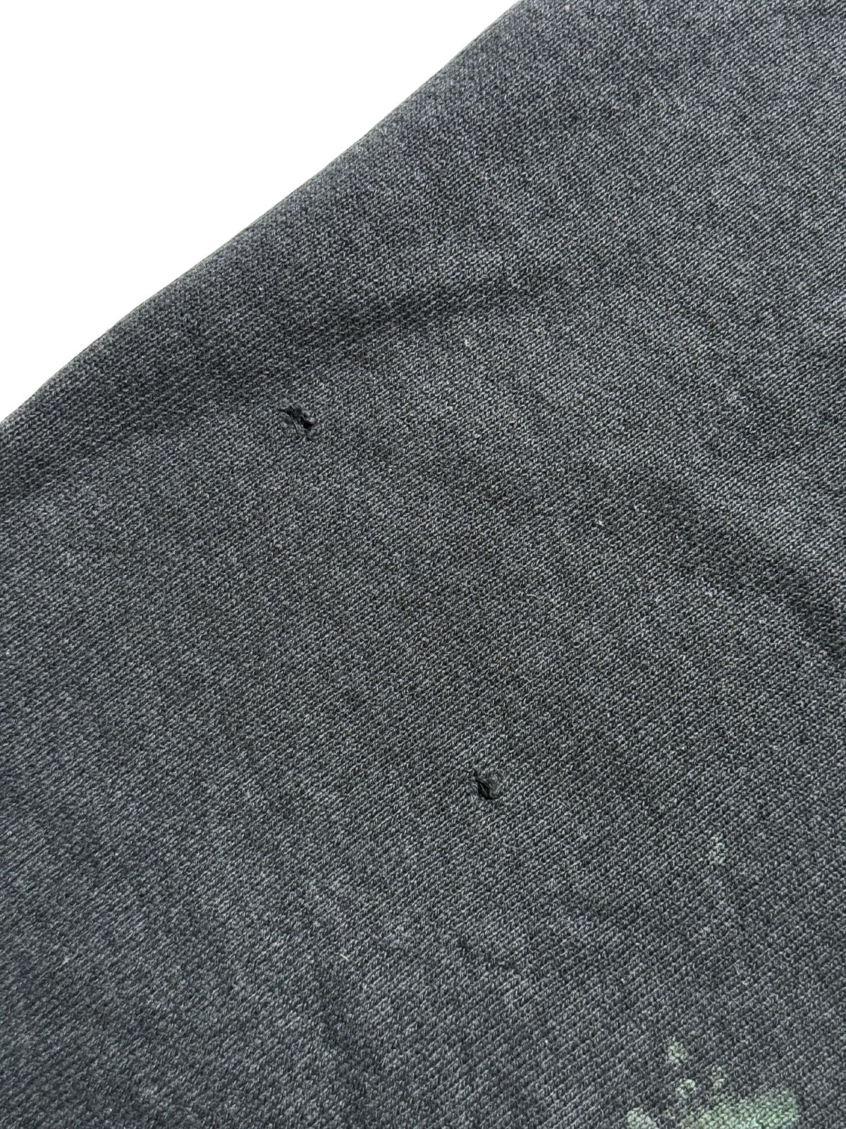 Makroaufnahme des Sweatshirt-Stoffs zur Zustandsdokumentation mit zwei kleinen Pinholes (Löchern) im Material.