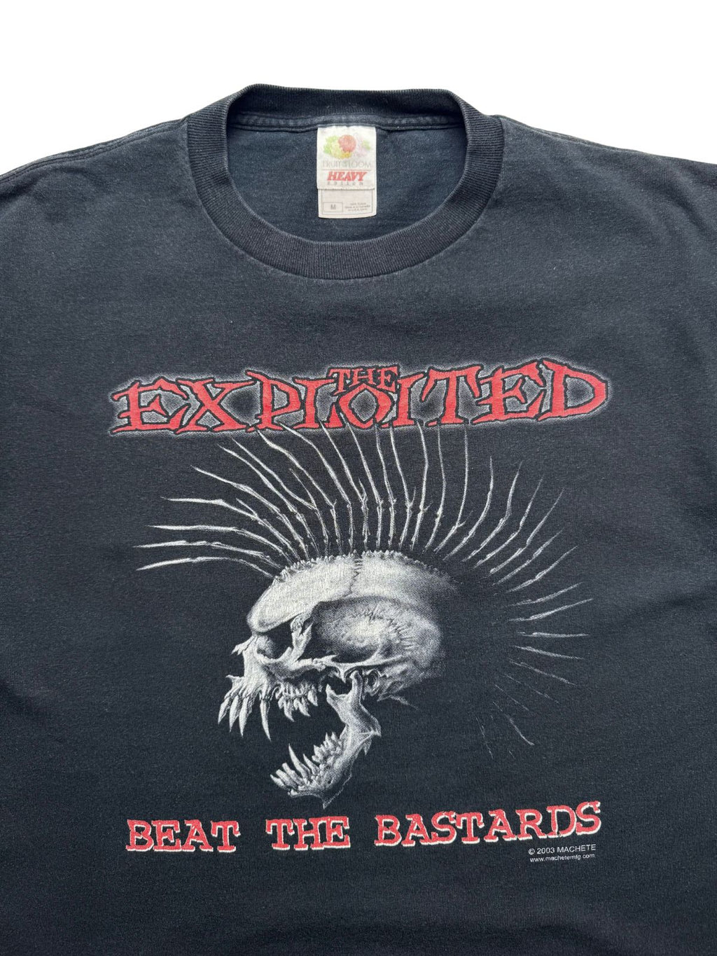 Detailansicht der vorderen Brustpartie mit geripptem Rundhalsausschnitt, dem „Fruit of the Loom“-Etikett und dem roten „THE EXPLOITED / BEAT THE BASTARDS“-Schriftzug samt Iro-Totenkopf.