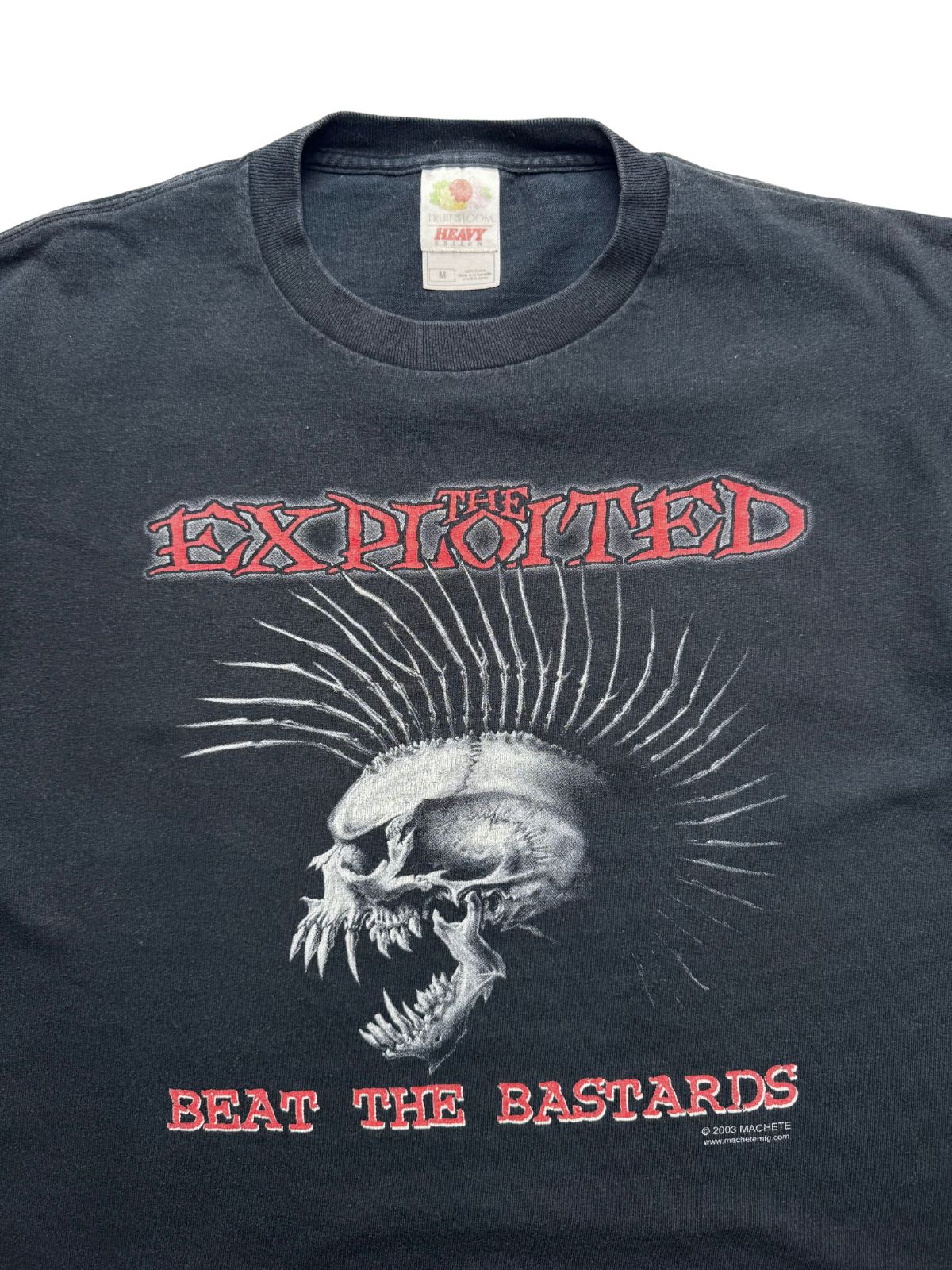Detailansicht der vorderen Brustpartie mit geripptem Rundhalsausschnitt, dem „Fruit of the Loom“-Etikett und dem roten „THE EXPLOITED / BEAT THE BASTARDS“-Schriftzug samt Iro-Totenkopf.