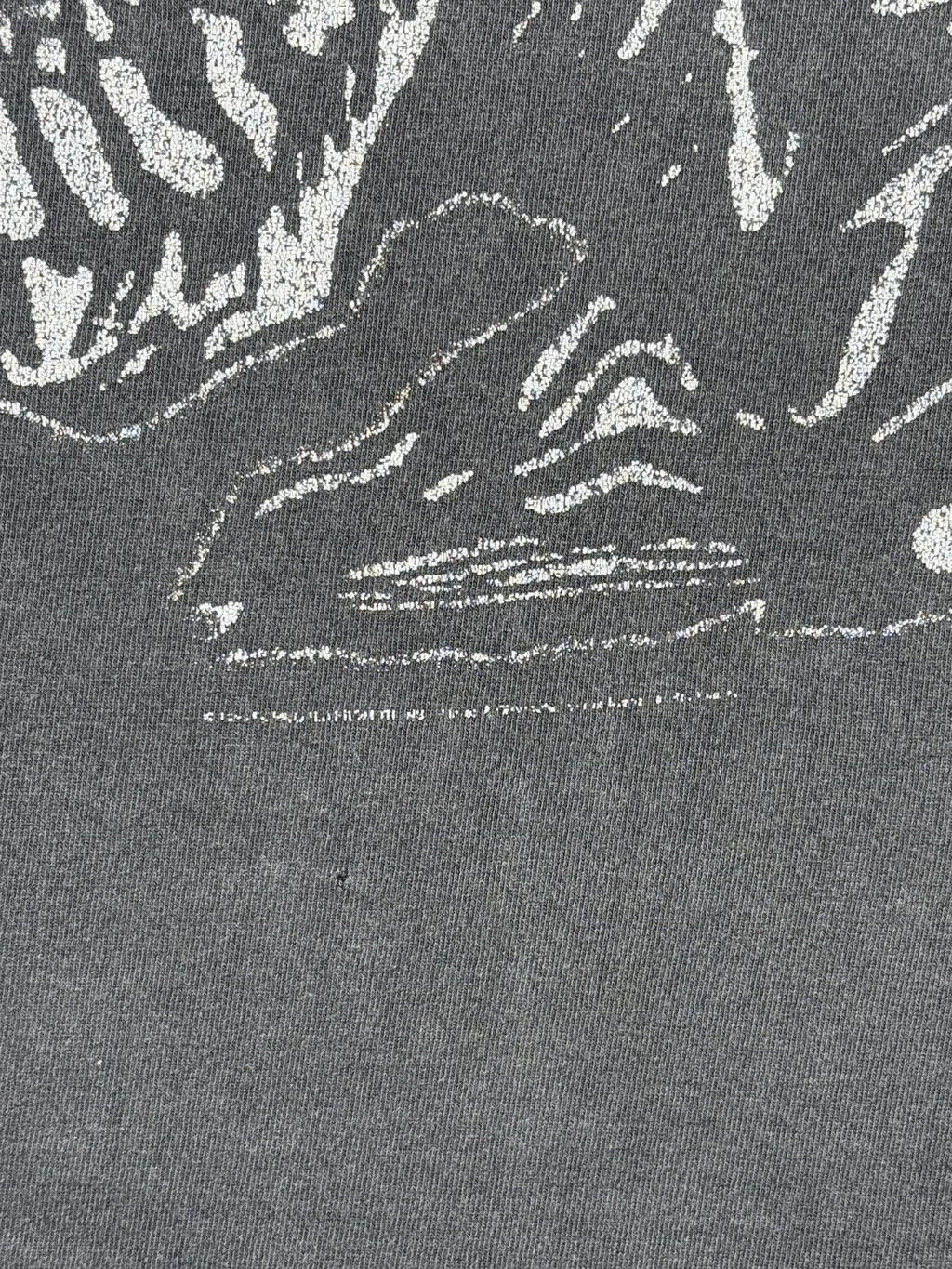Makroaufnahme eines stark verblassten, kaum noch lesbaren Copyright-Vermerks von 1998 unterhalb des vorderen Artworks sowie eines kleinen Lochs (Pinhole) im Stoff.
