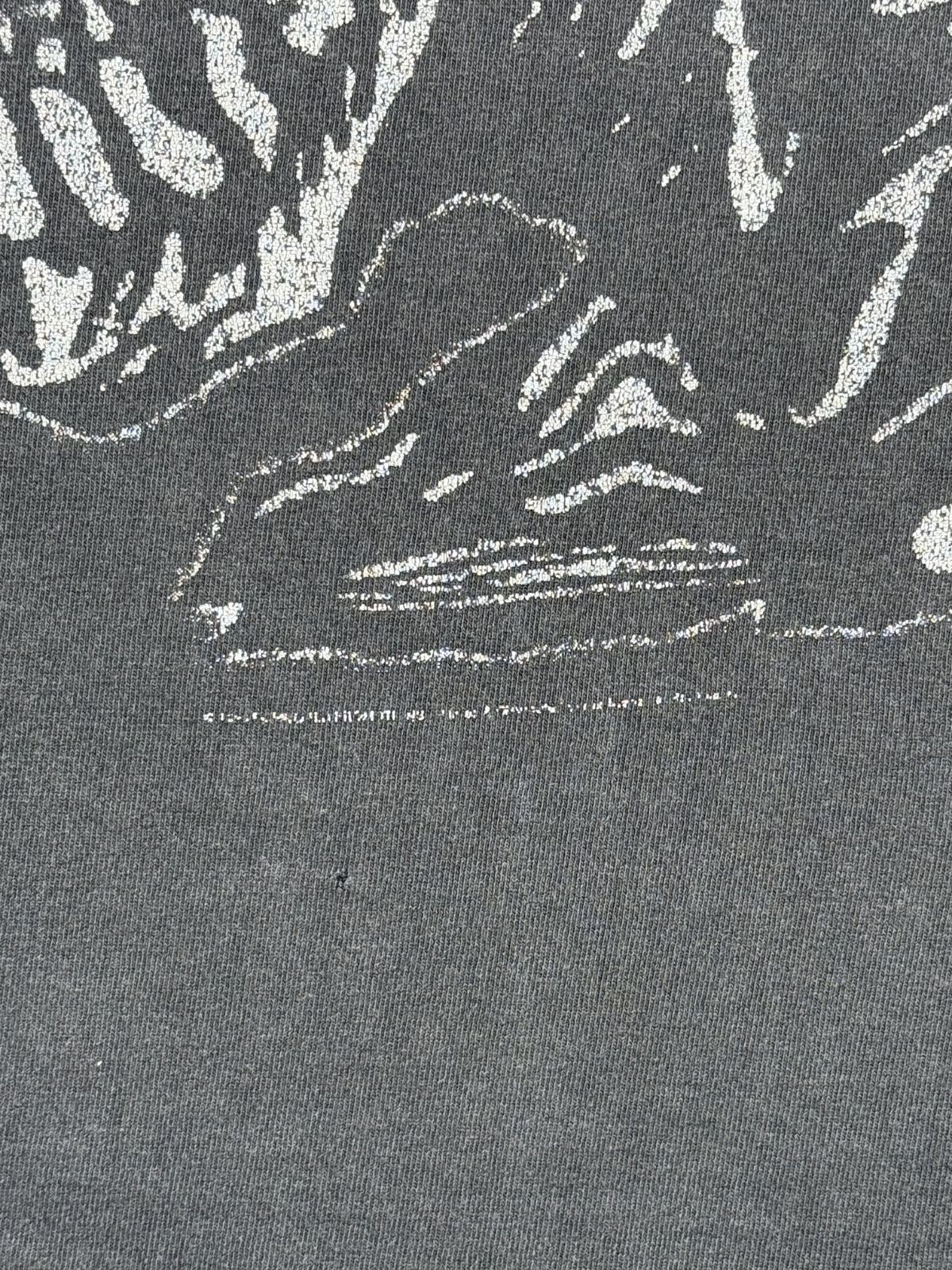 Makroaufnahme eines stark verblassten, kaum noch lesbaren Copyright-Vermerks von 1998 unterhalb des vorderen Artworks sowie eines kleinen Lochs (Pinhole) im Stoff.