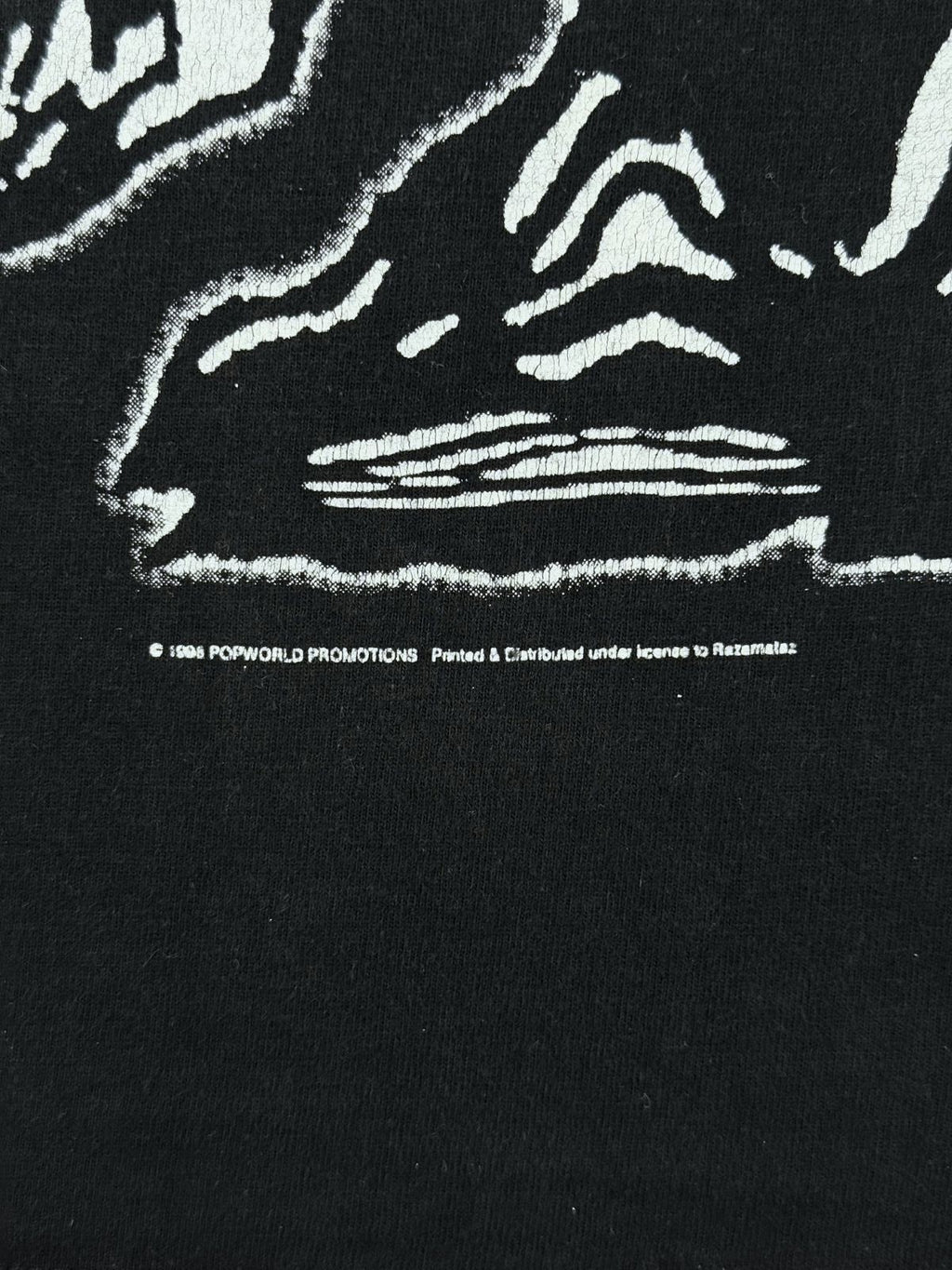 Makroaufnahme der Lizenzzeile unter dem Frontprint: „© 1998 POPWORLD PROMOTIONS - Printed & Distributed under license to Razamataz“.