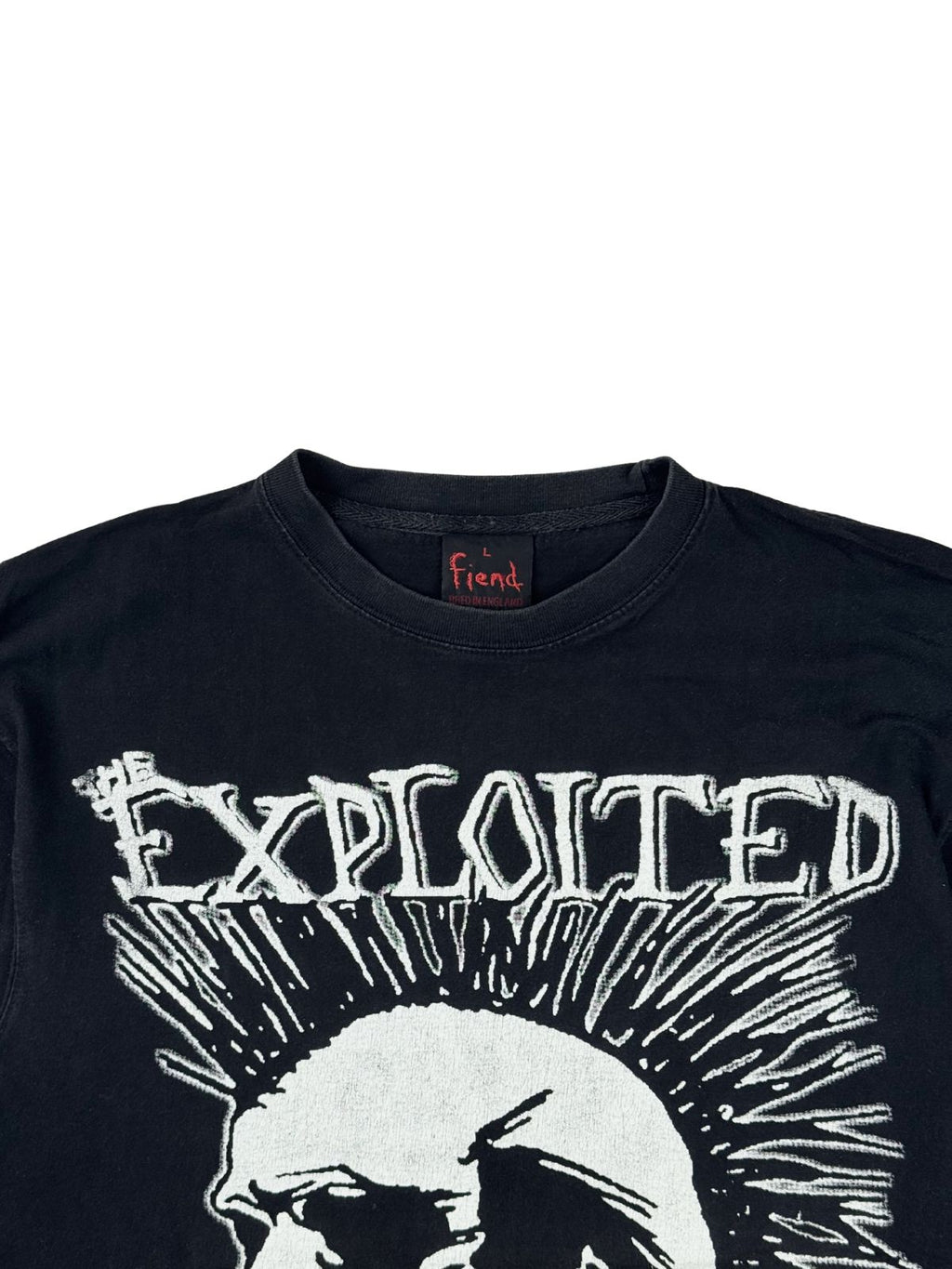 Nahaufnahme der oberen Vorderseite des Bandshirts mit Blick auf den gerippten Rundhalsausschnitt, das schwarze Fiend-Tag und den „THE EXPLOITED“-Schriftzug.