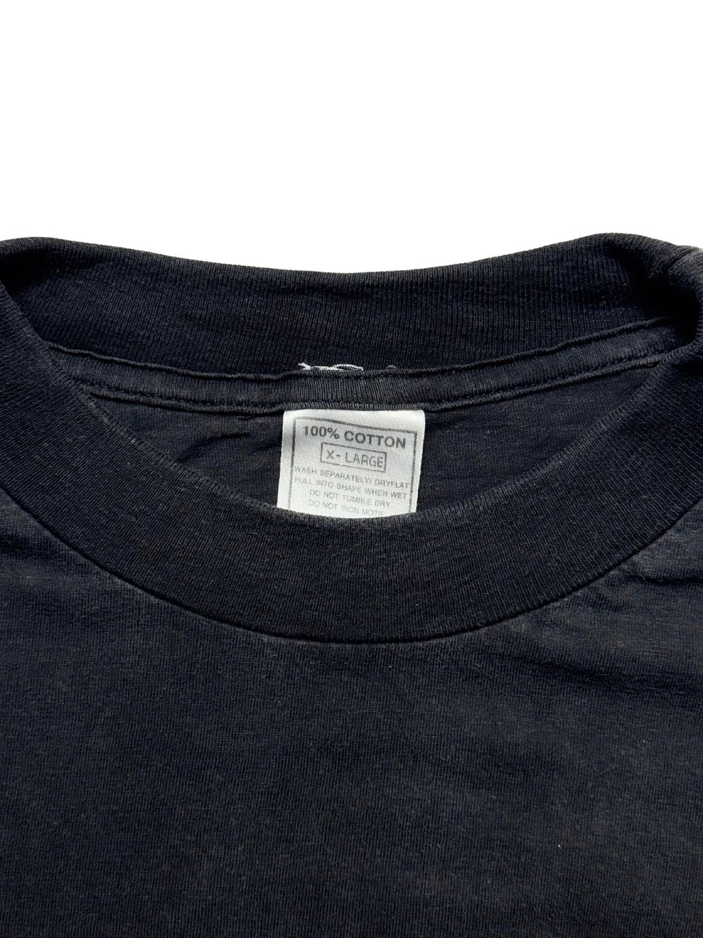 Nahaufnahme des Kragens mit dem originalen weißen Pflege-Etikett (100% COTTON / X-LARGE) auf dem schwarzen Baumwollstoff.