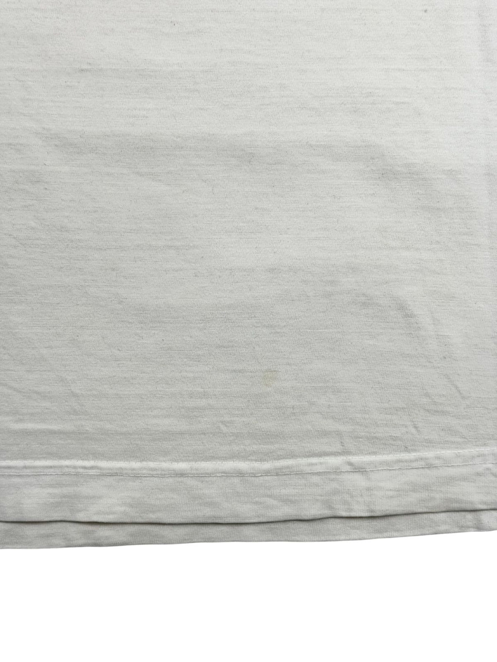Makroaufnahme des unteren Saums mit einem schwachen, hellbraunen Fleck direkt über der sichtbaren Doppelnaht des Vintage-T-Shirts.