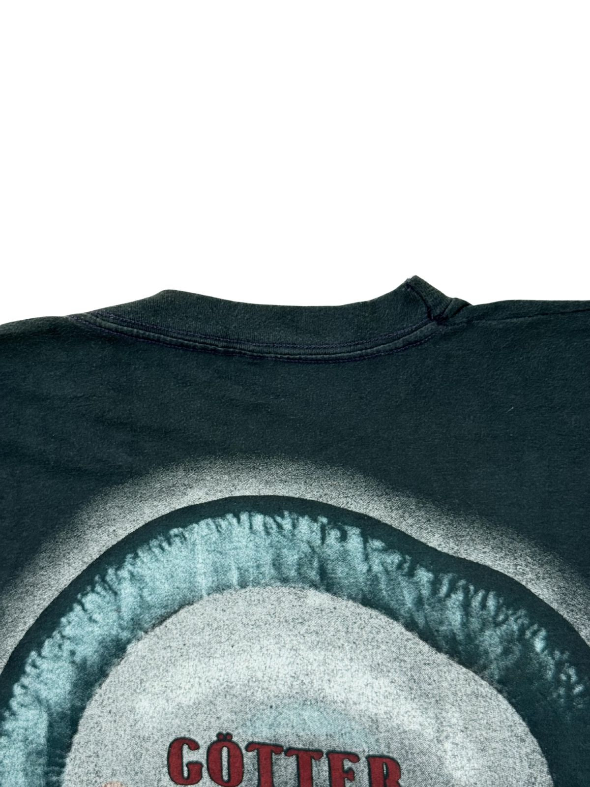 Detailaufnahme der Nackenpartie auf der Rückseite des ausgewaschenen Baumwollshirts direkt über der oberen Kante des kreisrunden Artworks.