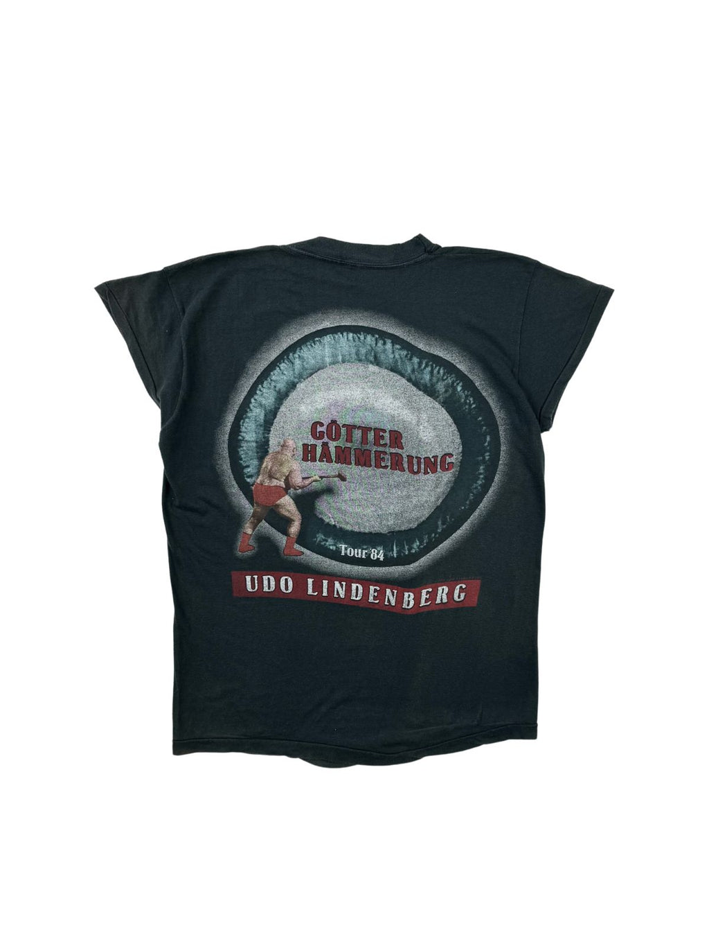 Rückseite des 1984er Udo Lindenberg Tour-Shirts mit farbigem „Götterhämmerung Tour '84“-Grafikprint, der einen Mann mit einem Vorschlaghammer in roter Unterhose zeigt.