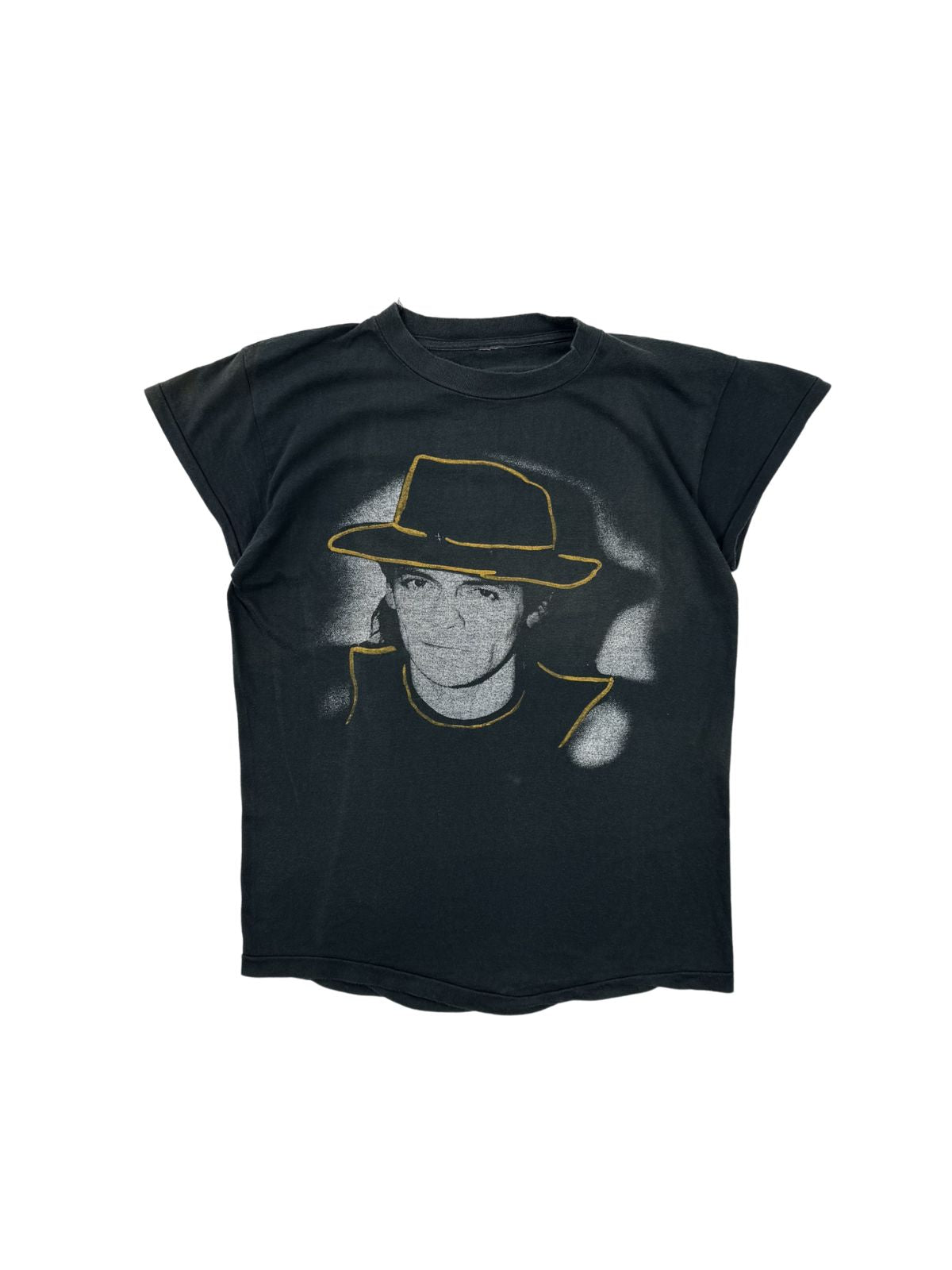 Originales Vintage Udo Lindenberg T-Shirt zur „Götterhämmerung“ Tour 1984. Schwarzes Krautrock-Bandshirt in der Frontansicht mit einem großen Porträt-Print von Udo Lindenberg samt ikonischem Hut mit gelber Outline.