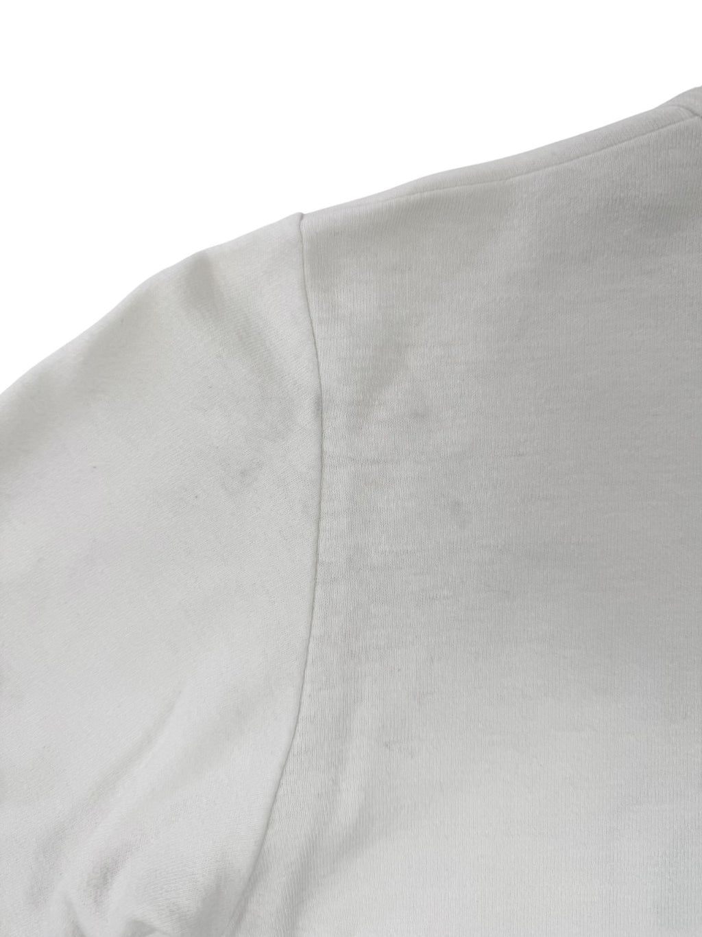 Detailaufnahme der Schulter- und Ärmelnaht; zeigt leichte, gelbliche Vintage-Flecken auf dem weißen Baumwollstoff.