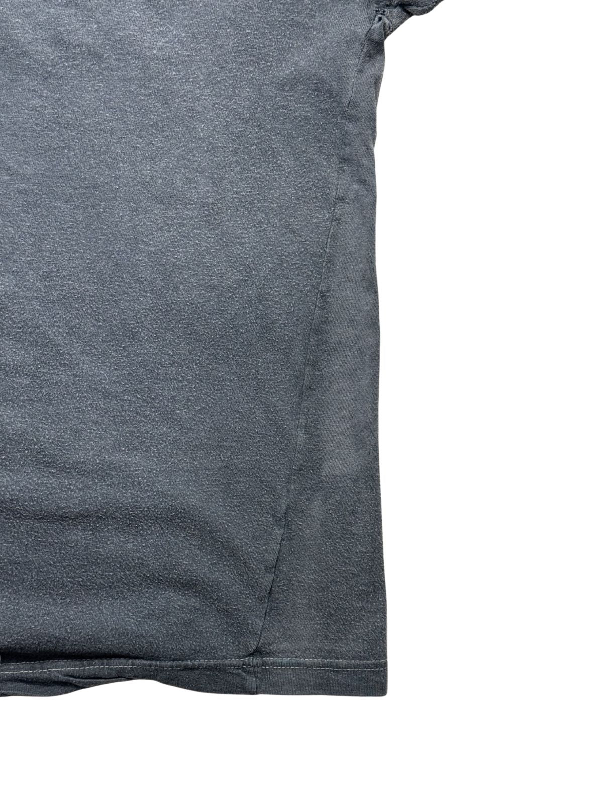 Detailansicht der seitlichen Körpernaht des verwaschenen schwarzen Baumwollshirts zur Veranschaulichung der Passform und Stoffstruktur.