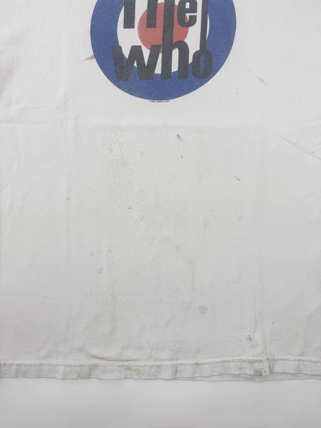 Großaufnahme der Vorderseite des weißen The Who Shirts; zeigt verstreute Vintage-Flecken und Verfärbungen unterhalb des Target-Logos auf dem Baumwollstoff.
